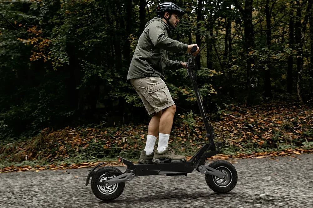 Man with helmet riding heavy duty off-road electric scooter on forest trail, autumn fallen leaves, outdoor adventure e-scooter